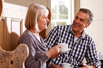 Lachendes sitzendes Paar bewältigt die COPD-Erkrankung des Mannes im Alltag
