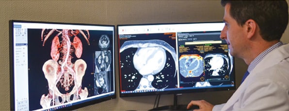 Facharzt prüft CT- und MR-Bilder an Bildschirm