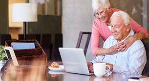 Am Tisch sitzendes älteres Ehepaar, das auf einem Laptop mehr über COPD liest