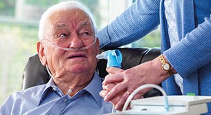 Sitzender Mann mit Nasenkanüle, der eine COPD-Behandlung erhält