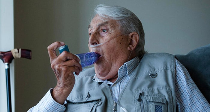 Älterer Mann mit Nasenkanüle, der zur Vermeidung von Schüben den OptiChamber Diamond Spacer anwendet