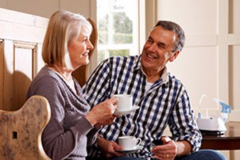 Lachendes sitzendes Paar bewältigt seine COPD-Erkrankung im Alltag