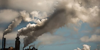 Skyline aus Fabrikschornsteinen mit Rauchschwaden, die die Luft verschmutzen