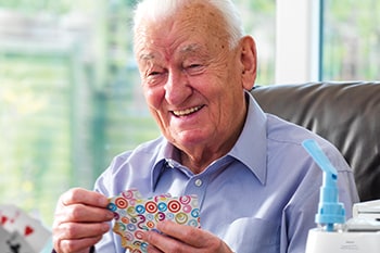 Lächelnder Mann spielt Karten dank COPD-Therapie