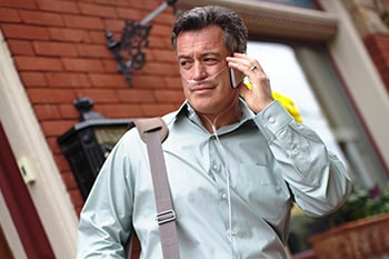 Ein Mann mit einer Nasenkanüle und einem SimplyGo tragbaren Sauerstoffkonzentrator telefoniert im Gehen am Handy