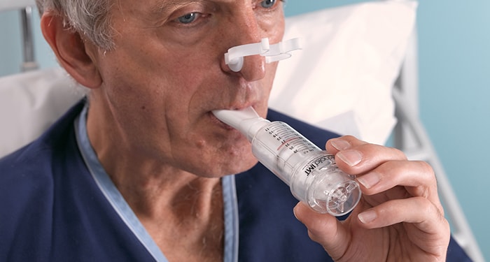 Gentleman strengthening his breathing muscles by using a Threshold IMT Muscle Trainer