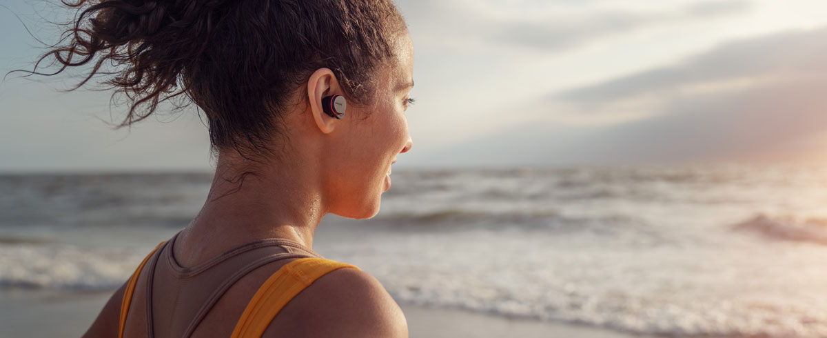 Frau trägt am Strand Philips True Wireless Sportkopfhörer