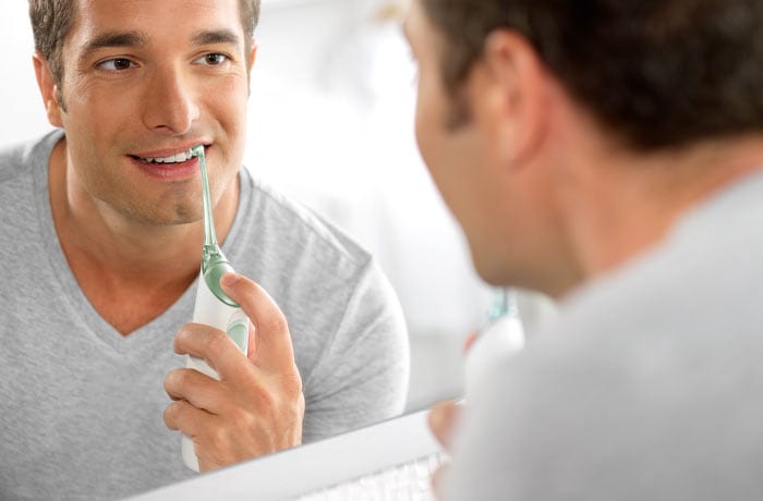 Ein Mann steht vor dem Spiegel und benutzt eine Philips Sonicare Airfloss