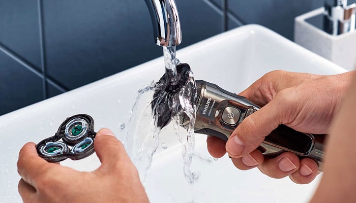 Mann reinigt den Philips Nassrasierer unter fließendem Wasser nach der Rasur.