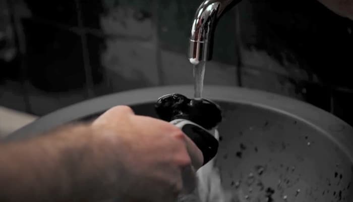 Eine Person wäscht einen Philips Rasierer unter fließendem Wasser nach der Rasur.
