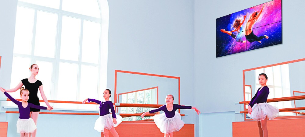 Digital Signage-Display an der Wand. Kinder lernen Ballett in einem Raum