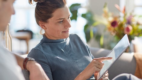 Frau auf Sofa schaut auf Tablet App (öffnet sich in einem neuen Fenster)