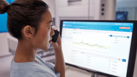 Mitarbeiterin im Gesundheitswesen vor dem Bildschirm am Telefon (öffnet sich in einem neuen Fenster)