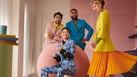 Mehrere Personen in farbenfrohen Kostümen stehen für ein Gruppenfoto.